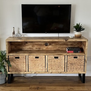 May include: A rustic wooden TV stand with four woven baskets and a shelf for storage. The stand has a black metal frame and is decorated with a giraffe and zebra figurine.