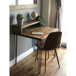 May include: A rustic wooden desk with a small shelf above the desktop. The desk has black hairpin legs and is paired with a brown chair. A globe, a potted plant, and a notebook are on the desk.
