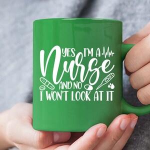 May include: Green ceramic mug with a white design that says "Yes I'm a Nurse and no I won't look at it". The design also includes a heart rate line, a bandage, a pill, a thermometer, and two drops of blood.