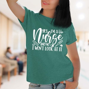 May include: A teal green t-shirt with the text "Yes, I'm a Nurse and no I won't look at it" in white. The text is surrounded by medical icons, including a bandage, a pill, a thermometer, and a heart.