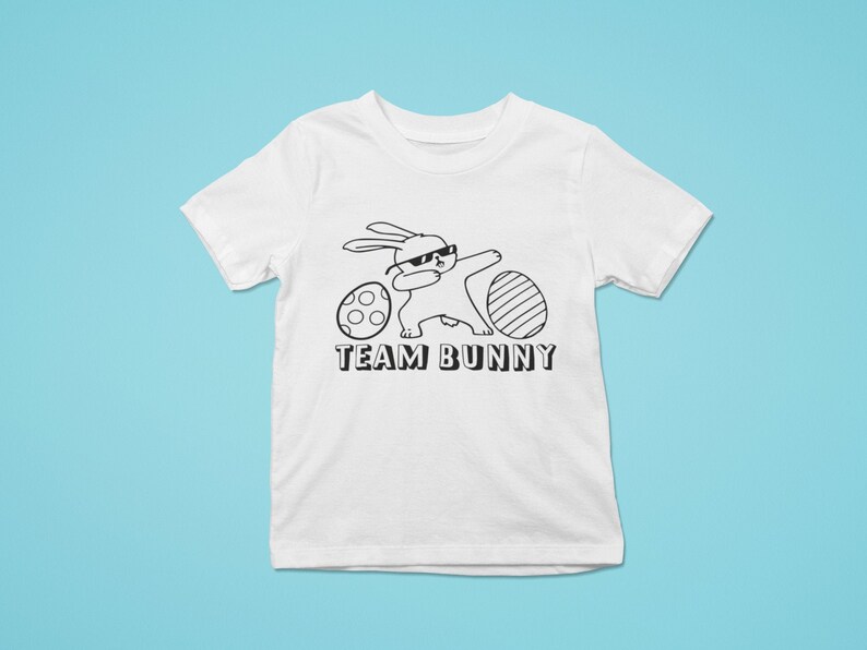 May include: White t-shirt featuring a black and white illustration of a bunny wearing sunglasses and holding an Easter egg. The text "TEAM BUNNY" is printed below the illustration.