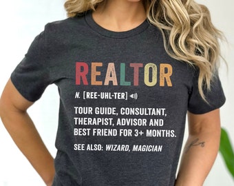 May include: A dark gray t-shirt with a vintage-style graphic that reads "REALTOR" with a definition: "N. [REE-UHL-TER] TOUR GUIDE, CONSULTANT, THERAPIST, ADVISOR AND BEST FRIEND FOR 3+ MONTHS. SEE ALSO: WIZARD, MAGICIAN"