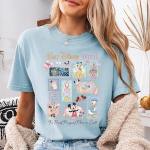 A woman wearing a light blue t-shirt with a Disney World-themed graphic printed on it.