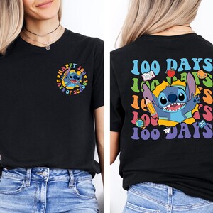 A woman wearing a black t-shirt with a colorful graphic design featuring a cartoon character and text related to the 100 Days of School.