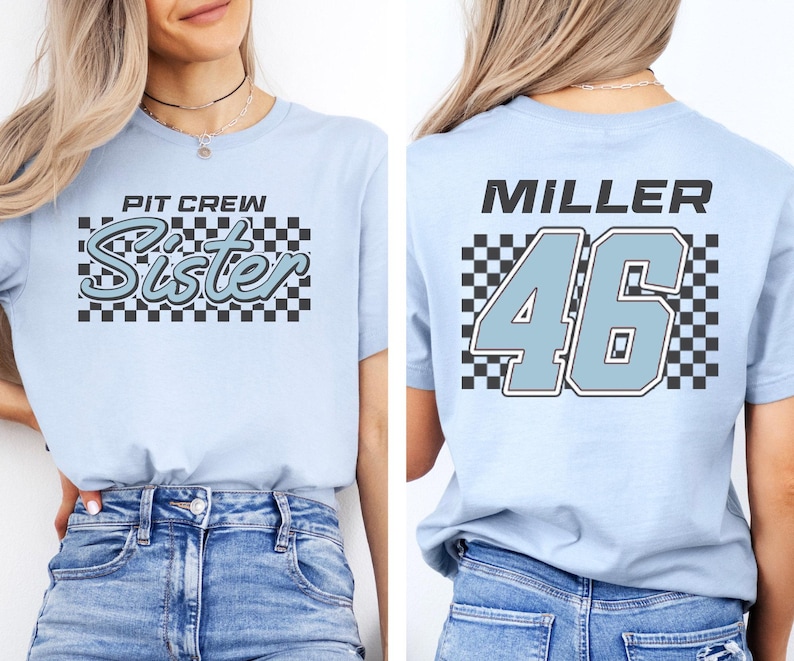 A woman wearing a light blue t-shirt with a checkered pattern and the text "PIT CIRCLE Sister" printed on it.