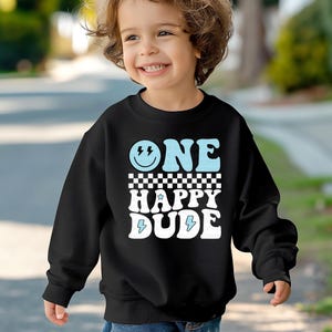 a young boy wearing a black sweatshirt that says one happy dude