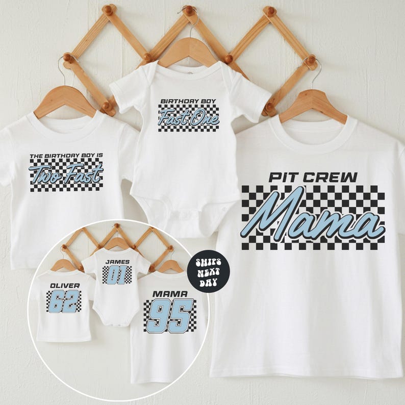 A collection of white t-shirts with various text and numbers printed on them, including a "PIT CREW Mama" t-shirt and a "The birthday boy is Tho fast" t-shirt. The t-shirts are displayed on wooden hangers against a white background.