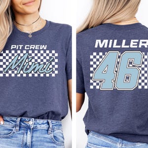 A woman wearing a gray t-shirt with the text "PIT CREW Mimi 46" printed on it.