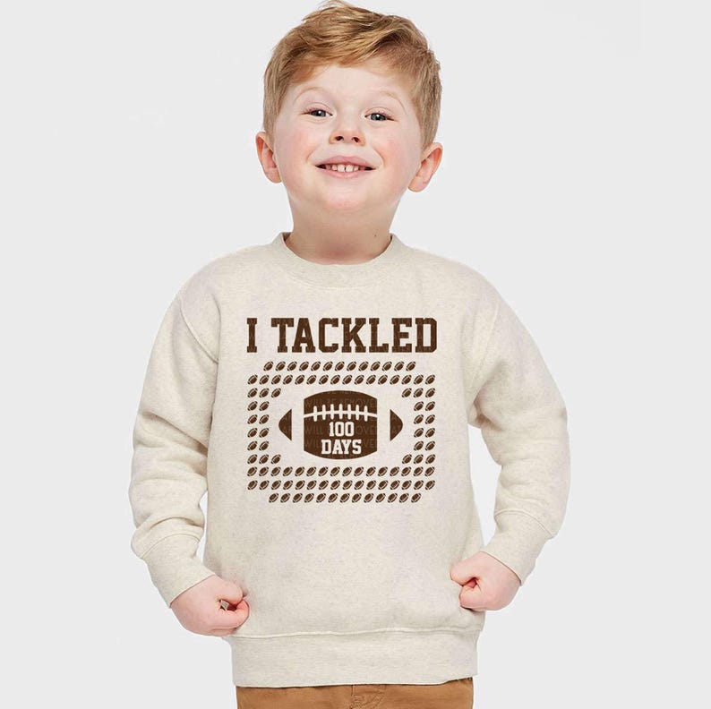 a young boy wearing a sweatshirt with a football on it
