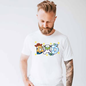 a man with a beard wearing a white shirt with the word dad printed on it