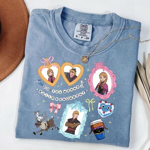 A blue t-shirt with various cartoon-style illustrations and text, including characters, objects, and phrases.