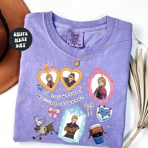 a purple t-shirt with various cartoon-style illustrations and text, including characters and objects such as a cup, a hat, and a snowman.