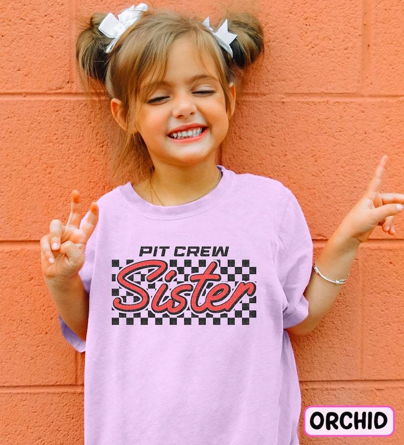 a little girl standing in front of a brick wall