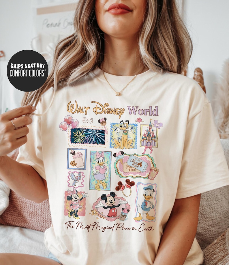 A woman wearing a white t-shirt with a Disney World-themed design, including various Disney characters and landmarks.
