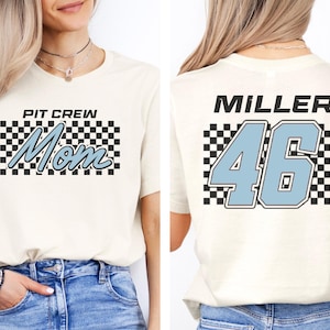 A woman wearing a white t-shirt with a checkered pattern and the text "PIT CREW Mom" printed on it.