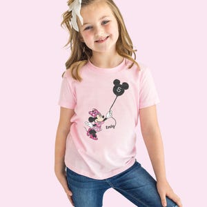 a little girl wearing a minnie mouse shirt