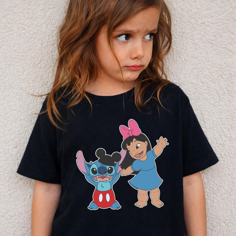 A young girl wearing a black t-shirt with a graphic of two cartoon characters, Stitch and Mickey Mouse, standing next to each other.
