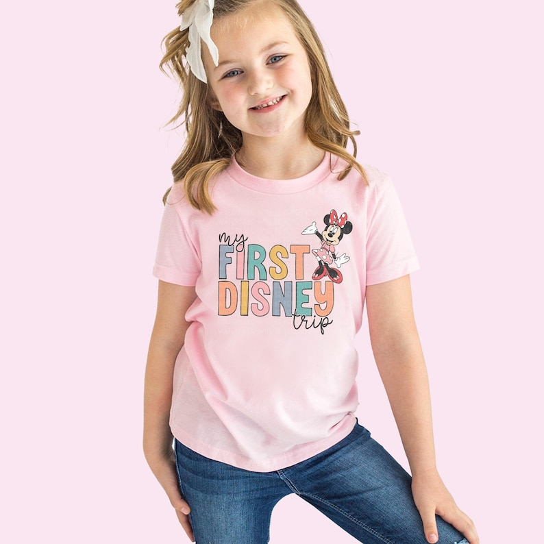 a little girl wearing a pink shirt with a minnie mouse on it