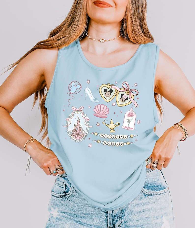 A woman wearing a light blue tank top with various Disney-themed illustrations and accessories, including a castle, Mickey Mouse, and other whimsical elements.
