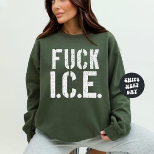 a woman wearing a sweatshirt that says fuck ice