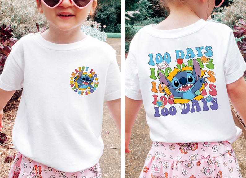 A young girl wearing a white t-shirt with a colorful graphic design featuring a cartoon character and text.