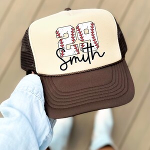 a person holding a hat with a baseball on it