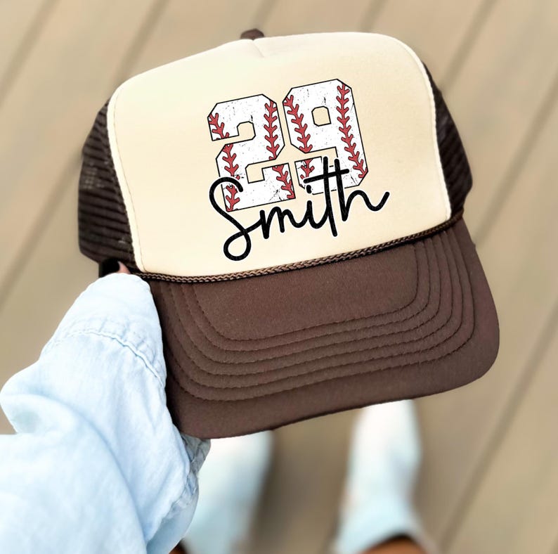 a person holding a hat with a baseball on it