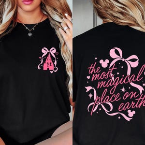 a woman wearing a black t-shirt with a pink design and text on the back.
