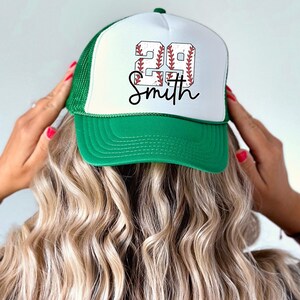 a woman putting on a baseball hat with the word go smith on it