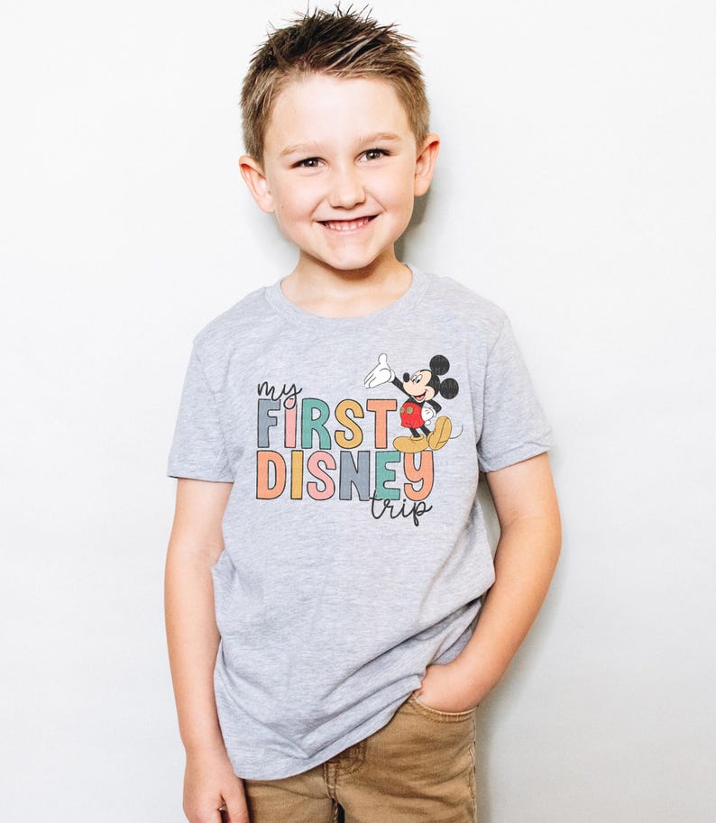 a young boy standing in front of a white wall
