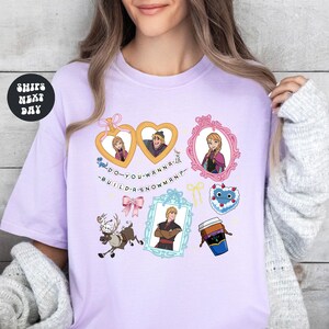 A woman wearing a pink t-shirt with various cartoon characters and text printed on it.
