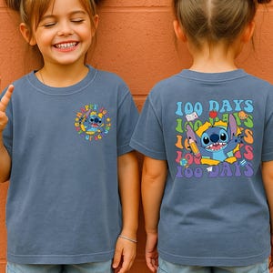 A young girl wearing a blue t-shirt with a cartoon character and text printed on it.