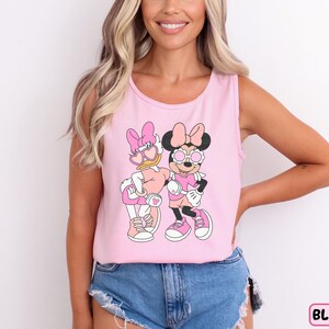 a woman wearing a pink tank top with mickey and minnie mouse on it