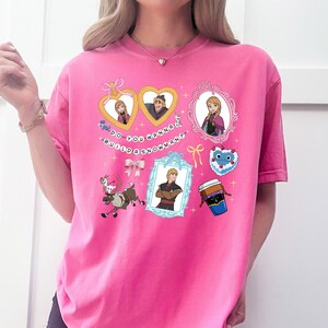 A pink t-shirt with various cartoon-style illustrations and text, including characters, objects, and phrases.