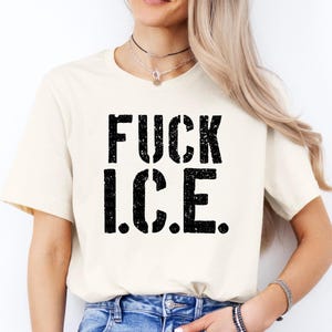 a woman wearing a white t - shirt that says fuck ice