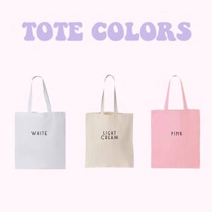 three tote bags in different colors: white, light cream, and pink.