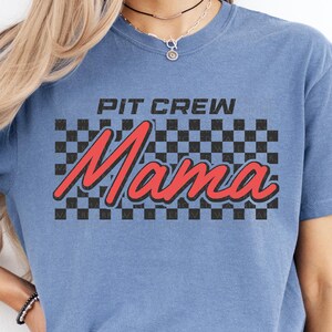 a woman wearing a blue t - shirt that says pit crew mama