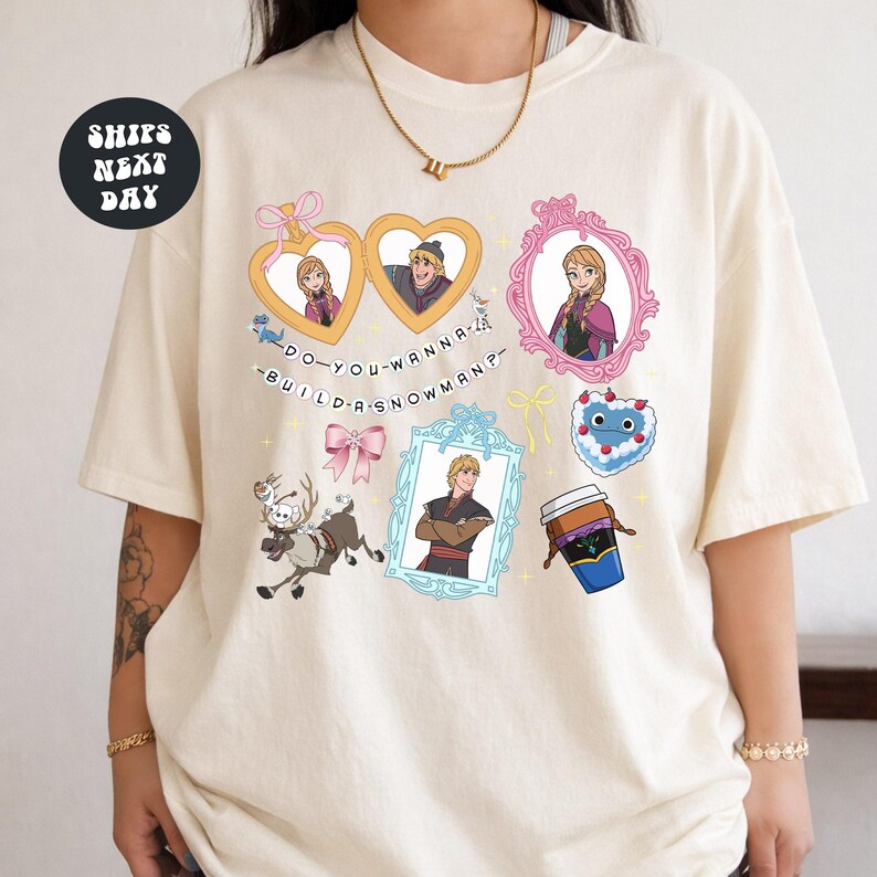 A person wearing a white t-shirt with various cartoon-style illustrations and text, including characters and objects such as hearts, a cup, and a snowman.
