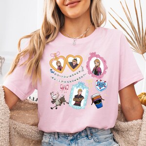 A woman wearing a pink t-shirt with various cartoon characters and designs printed on it.