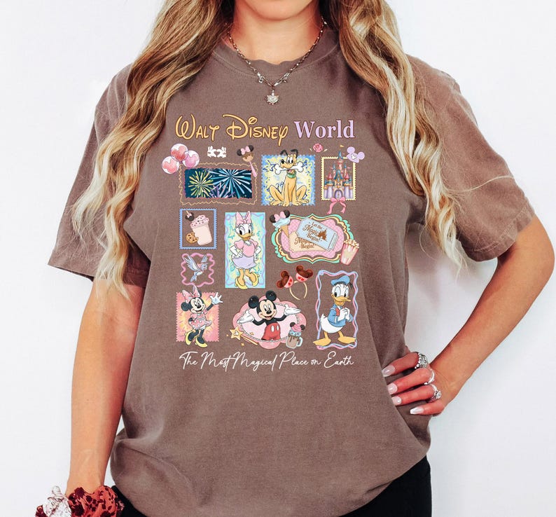 A woman wearing a t-shirt with a Disney World-themed design, including various Disney characters and landmarks.
