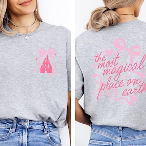 a woman wearing a gray t-shirt with a pink castle graphic and text on the back.