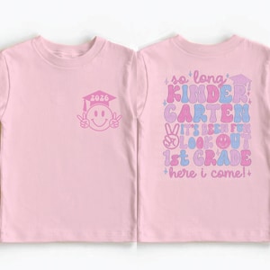 A pink t-shirt with a graduation cap and smiley face design, along with text that says "so long Kindergarten Carten, it's been fun looking out 1st Grade here I come!"