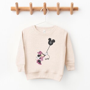 a sweater with a minnie mouse on it hanging on a clothes rack