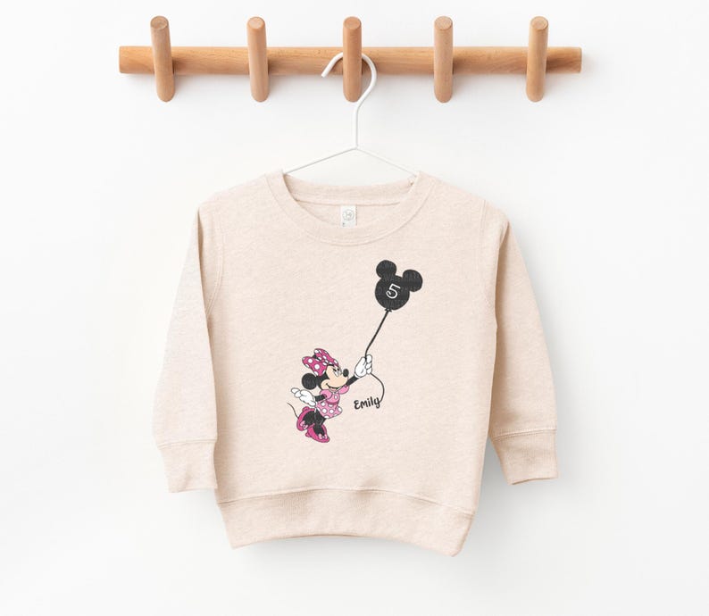 a sweater with a minnie mouse on it hanging on a clothes rack