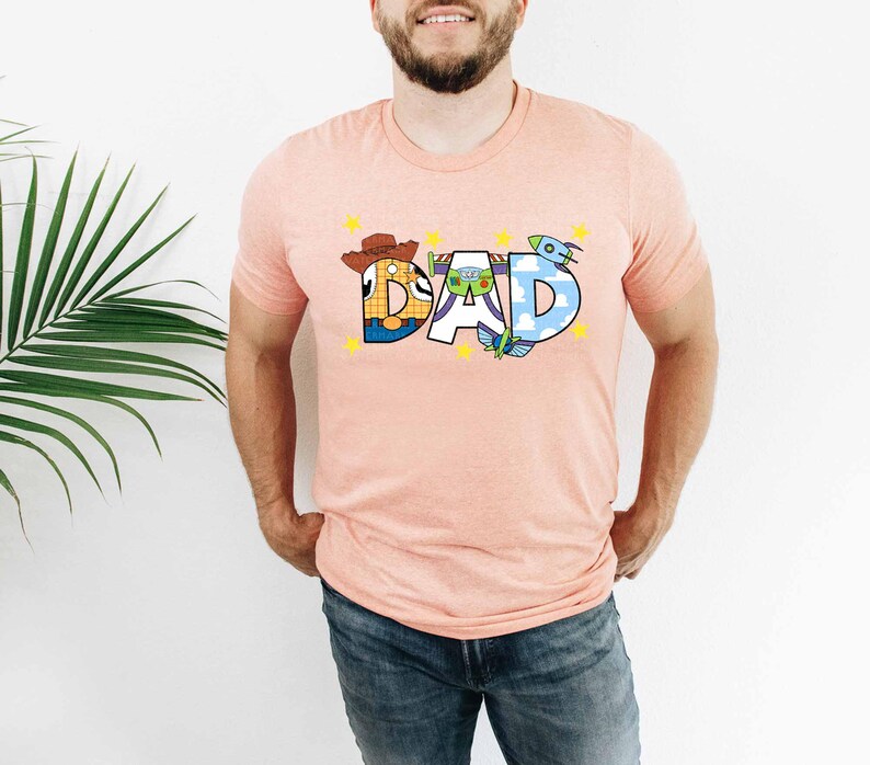 a man standing in front of a plant wearing a pink shirt with the word dad