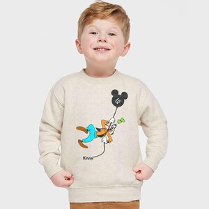 a young boy wearing a mickey mouse sweatshirt