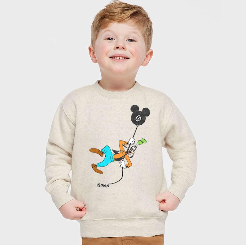 a young boy wearing a mickey mouse sweatshirt
