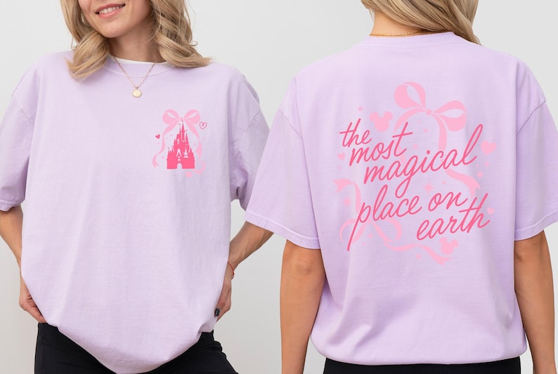 A woman wearing a pink t-shirt with a castle and bow design on the front and text on the back.