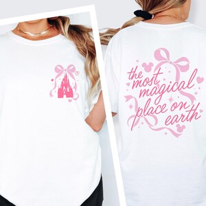 A white t-shirt with a pink castle graphic and text on the back.
