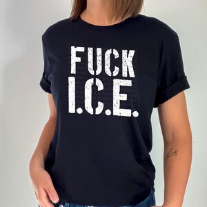 a woman wearing a black t - shirt with the words fuck ice printed on it